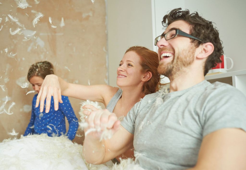 a happy middle aged couple celebrate a successful pillow fight with their daughter thanks to a renewed vitality with bhrt pittsburgh therapies.