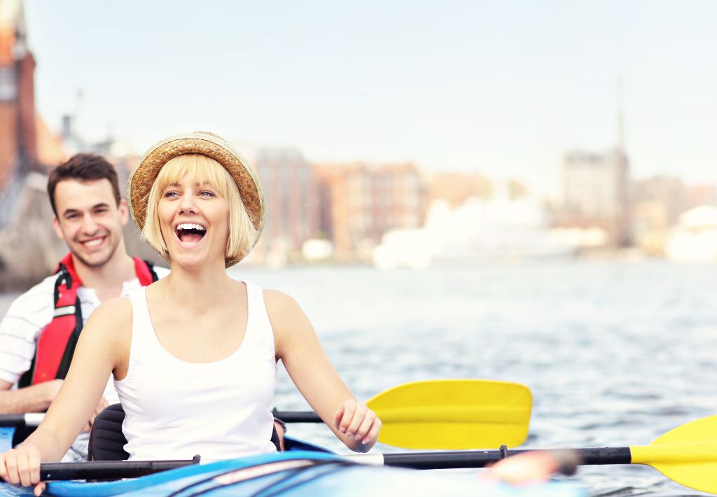 two happy people are in a canoe and hold yellow paddles as they float along by the steel city waterfront thanks to quality functional medicine pittsburgh that makes them feel great.