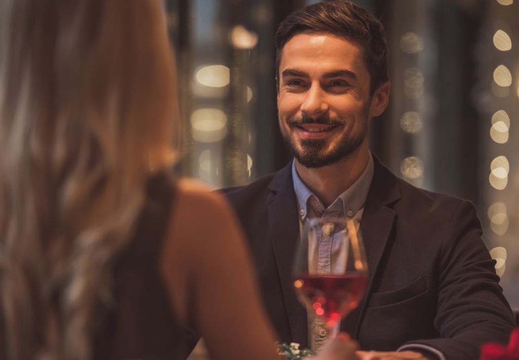 a confident man looks across the table in a nice restaurant at his date. TRT murrysville treatments have him feeling confident and ready