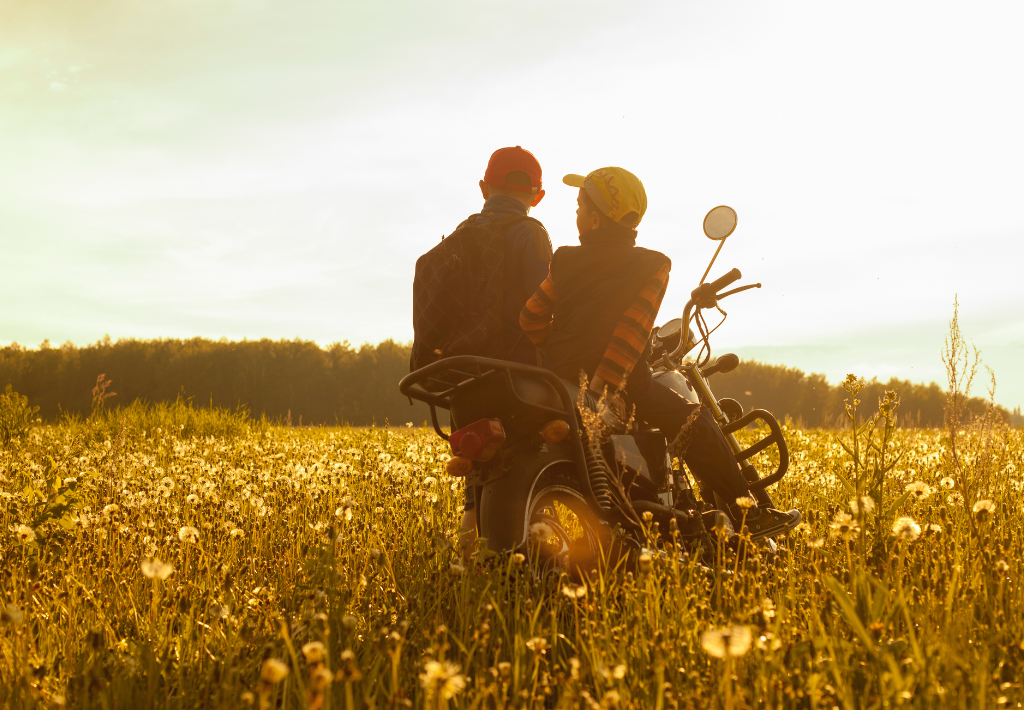 a couple sits aside their motorcycle in a field of yellow flowers watching the sunset thanks to mcmurray functional medicine - keeping them feeling healthy for the future.